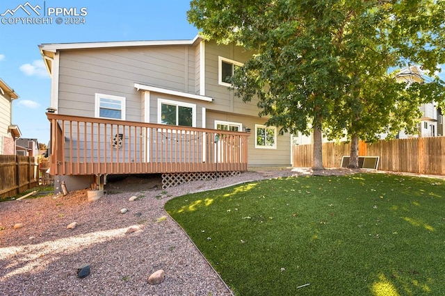 rear view of property featuring a deck and a lawn