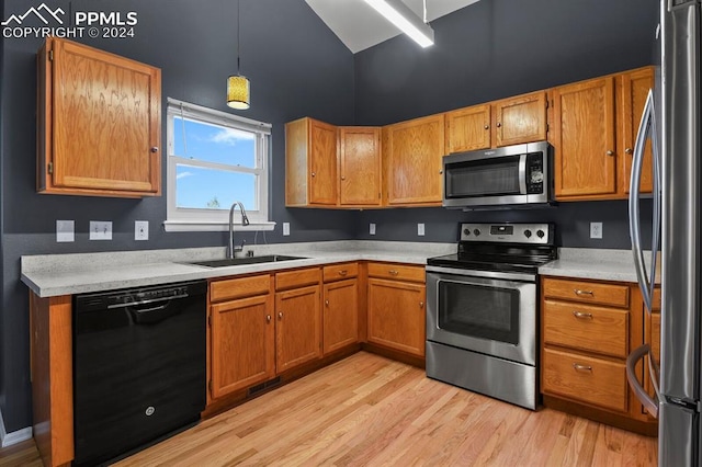 kitchen with light hardwood / wood-style floors, appliances with stainless steel finishes, decorative light fixtures, and sink