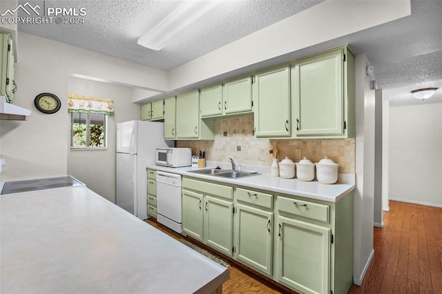 kitchen with backsplash, white appliances, a textured ceiling, dark hardwood / wood-style floors, and sink