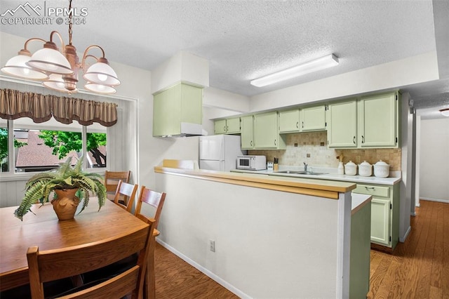 kitchen featuring a notable chandelier, green cabinets, white appliances, and sink