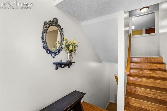 stairs with a textured ceiling and vaulted ceiling