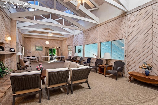 dining space featuring wood walls, carpet flooring, beam ceiling, ceiling fan, and a skylight