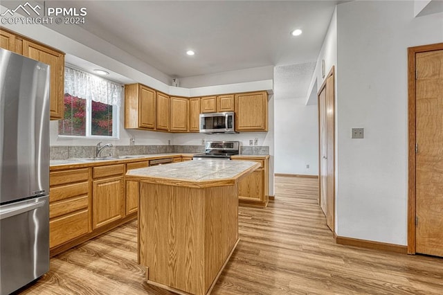 kitchen with a kitchen island, light hardwood / wood-style floors, sink, and appliances with stainless steel finishes