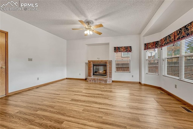 unfurnished living room with a fireplace, light hardwood / wood-style floors, a textured ceiling, and ceiling fan