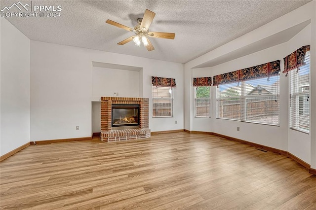 unfurnished living room featuring a textured ceiling, light hardwood / wood-style flooring, a wealth of natural light, and ceiling fan