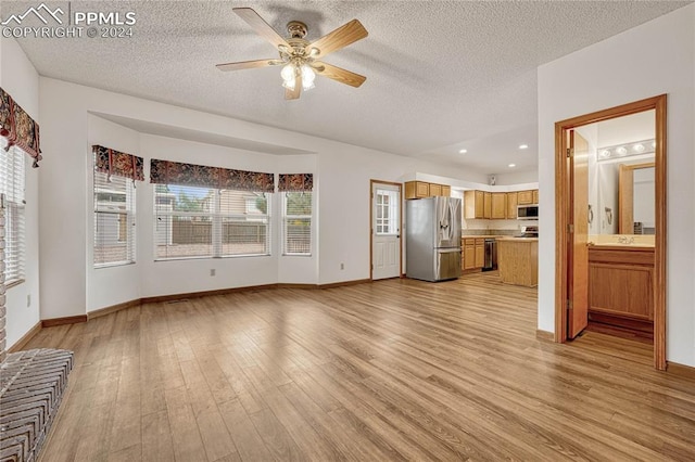 unfurnished living room with ceiling fan, a textured ceiling, and light wood-type flooring