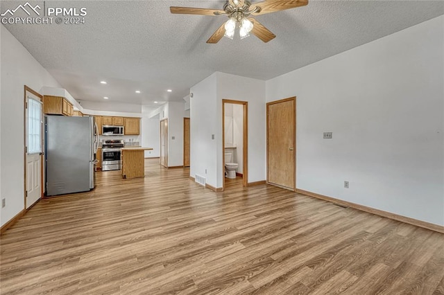 unfurnished living room featuring ceiling fan, light wood-type flooring, and a textured ceiling