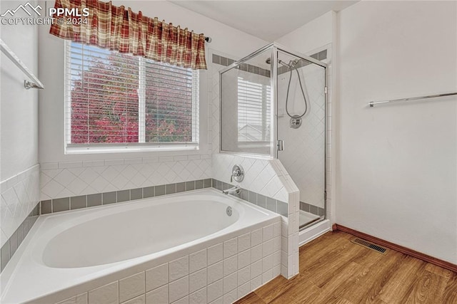 bathroom featuring wood-type flooring and shower with separate bathtub