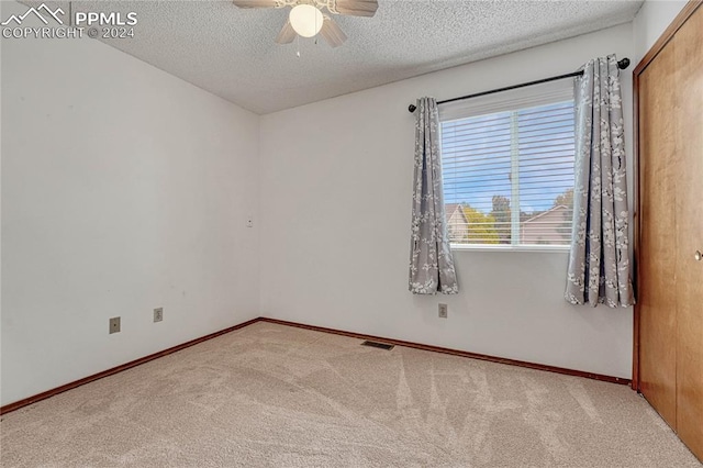 empty room featuring carpet, ceiling fan, and a textured ceiling