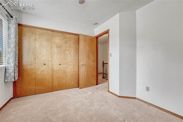 unfurnished bedroom featuring a textured ceiling, carpet floors, and a closet