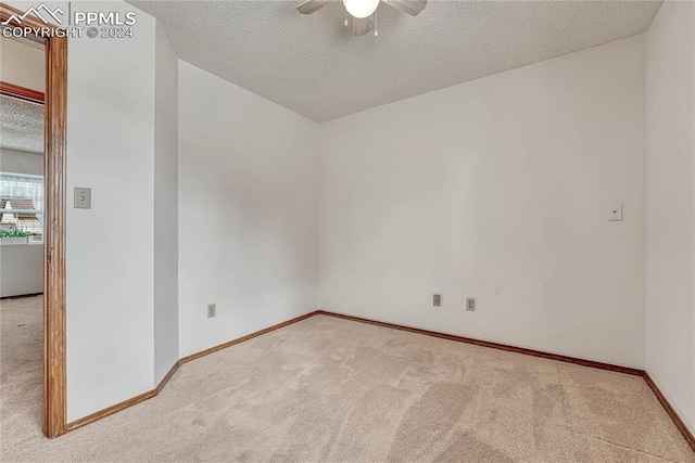 unfurnished room with ceiling fan, a textured ceiling, and light carpet