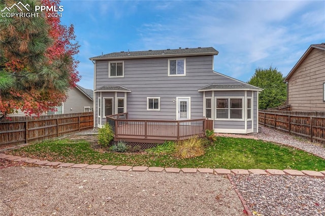 rear view of house featuring a yard, a wooden deck, and a sunroom