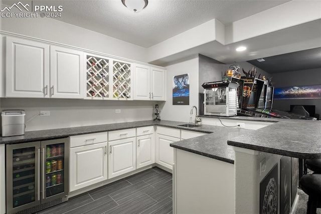8032 Wheatland Dr, Colorado Springs, CO 80908 - kitchen featuring a breakfast bar, a peninsula, white cabinetry, wine cooler, and a sink