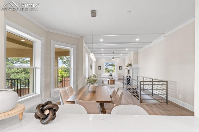 dining room with light wood-type flooring, crown molding, and beam ceiling