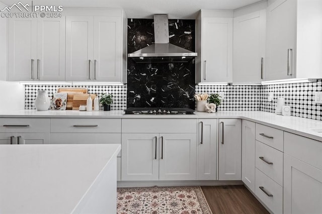 kitchen with wall chimney exhaust hood, black gas cooktop, white cabinetry, and decorative backsplash