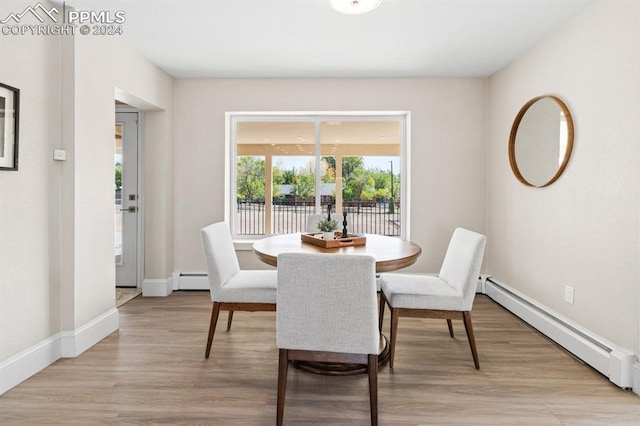 dining area with light hardwood / wood-style flooring and a baseboard heating unit