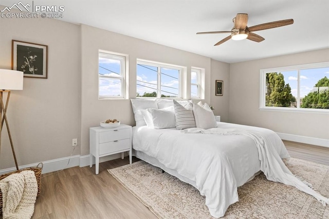 bedroom with ceiling fan, light wood-type flooring, and multiple windows