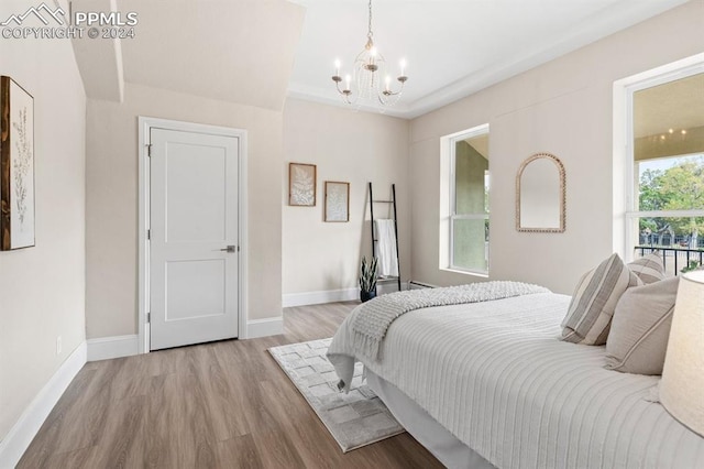 bedroom with a notable chandelier, light hardwood / wood-style floors, and multiple windows