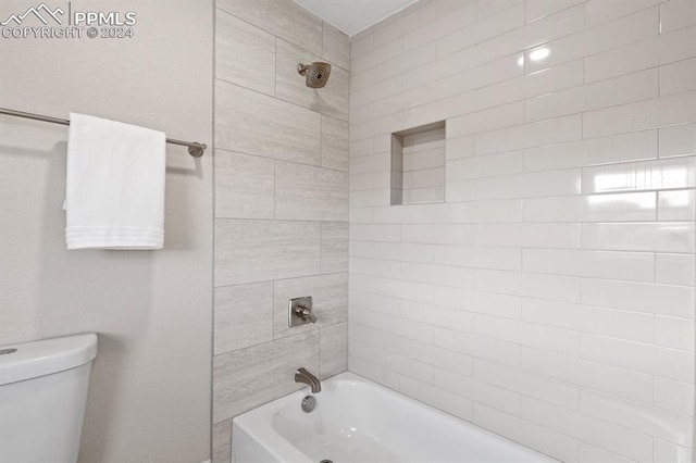 bathroom featuring toilet and tiled shower / bath