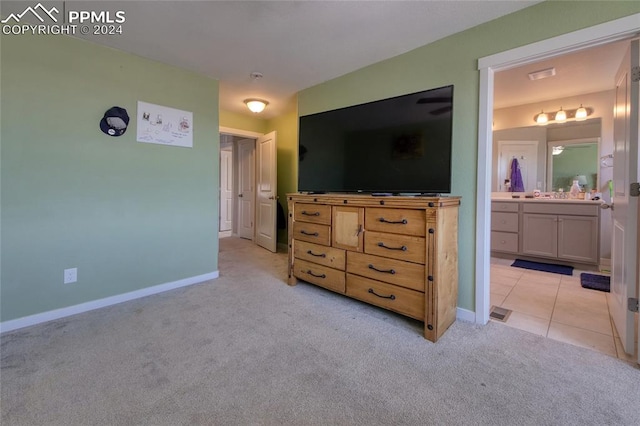 bedroom featuring connected bathroom and light colored carpet