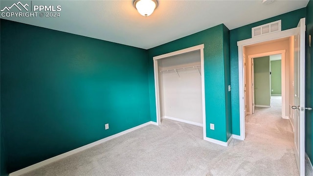 unfurnished bedroom with a closet and light colored carpet