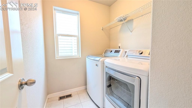 clothes washing area with independent washer and dryer and light tile patterned floors