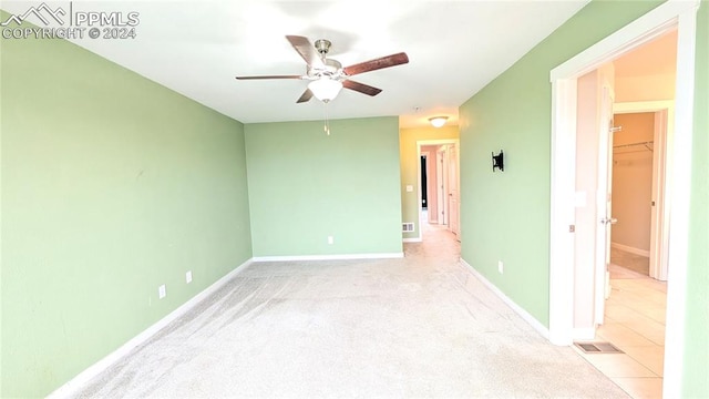 empty room featuring ceiling fan and light colored carpet