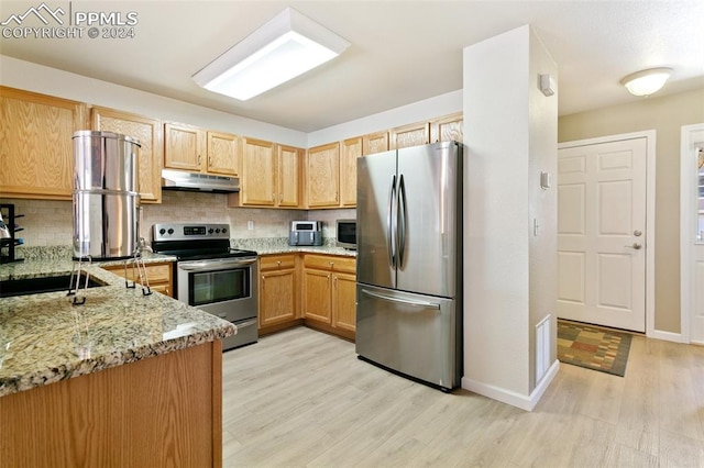 kitchen with light wood-type flooring, tasteful backsplash, sink, appliances with stainless steel finishes, and light stone countertops