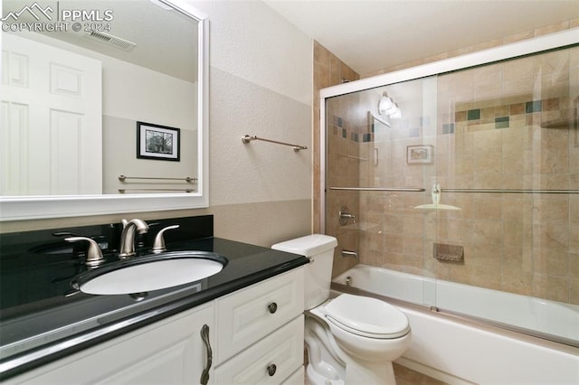 full bathroom featuring enclosed tub / shower combo, vanity, and toilet