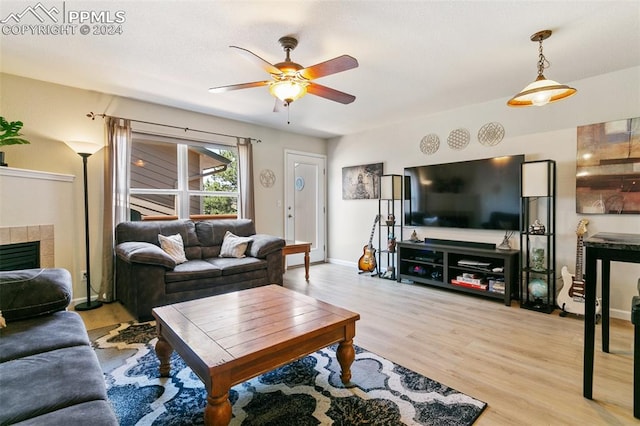 living room featuring light wood-type flooring, ceiling fan, and a fireplace