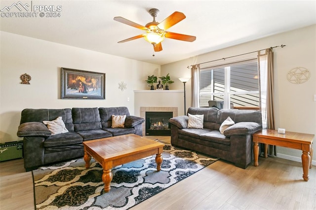 living room featuring ceiling fan, a fireplace, and light hardwood / wood-style floors