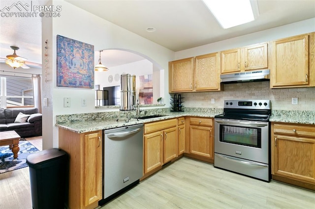 kitchen featuring appliances with stainless steel finishes, hanging light fixtures, light hardwood / wood-style floors, backsplash, and ceiling fan