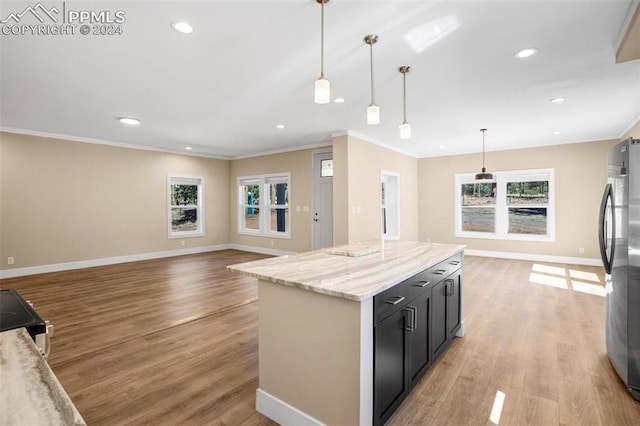 kitchen with light wood-type flooring, stainless steel fridge, pendant lighting, and light stone counters