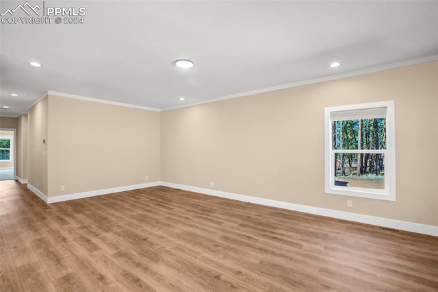 spare room featuring a healthy amount of sunlight, crown molding, and light hardwood / wood-style flooring