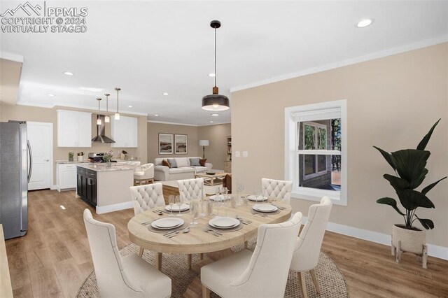 dining space featuring ornamental molding and light hardwood / wood-style flooring