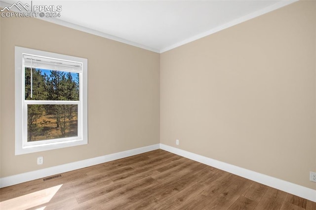 unfurnished room with wood-type flooring and ornamental molding