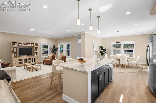 kitchen with pendant lighting, stainless steel refrigerator, light stone countertops, and light hardwood / wood-style floors