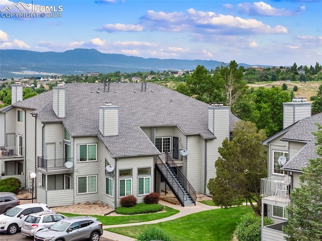 view of front of property featuring a balcony, a mountain view, and a front yard