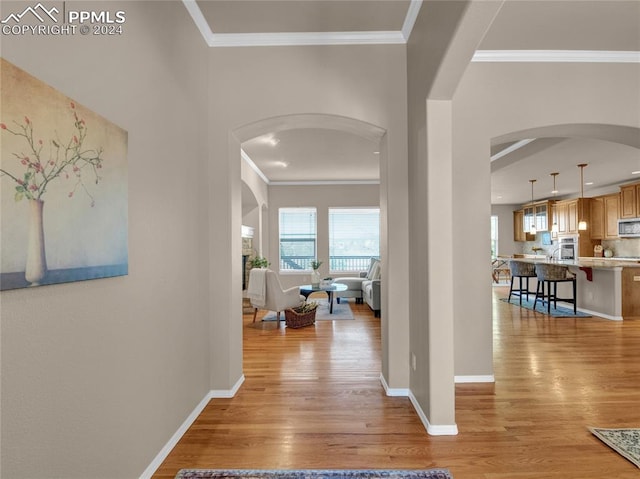 hall with crown molding and light hardwood / wood-style floors