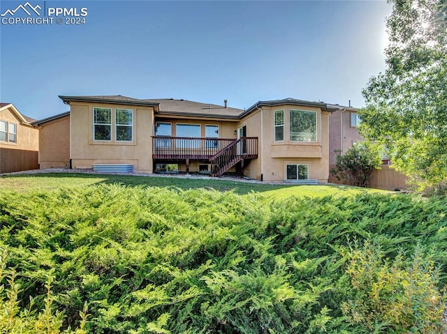 rear view of house featuring a deck and a lawn