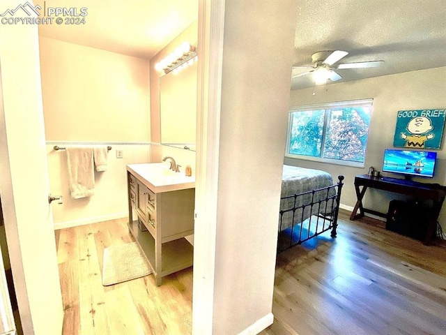 bathroom with a textured ceiling, hardwood / wood-style floors, vanity, and ceiling fan