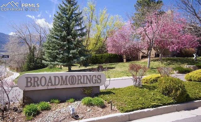 community / neighborhood sign featuring a mountain view and a lawn