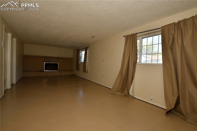 unfurnished living room featuring a brick fireplace, concrete floors, and a textured ceiling