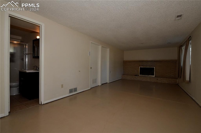 unfurnished living room featuring a textured ceiling and a fireplace