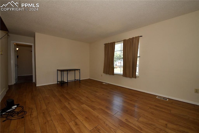 unfurnished room featuring a textured ceiling and hardwood / wood-style floors