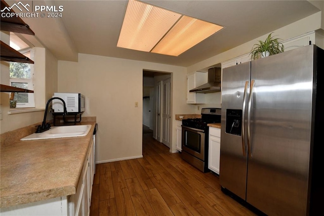 kitchen featuring hardwood / wood-style flooring, sink, white cabinets, wall chimney range hood, and stainless steel appliances