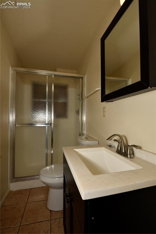 bathroom featuring tile patterned flooring, vanity, toilet, and a shower with shower door