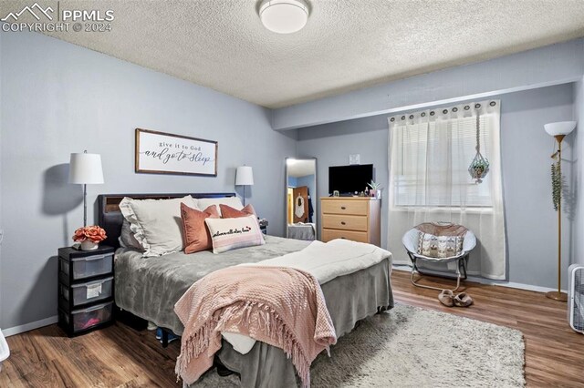 bedroom with hardwood / wood-style flooring and a textured ceiling