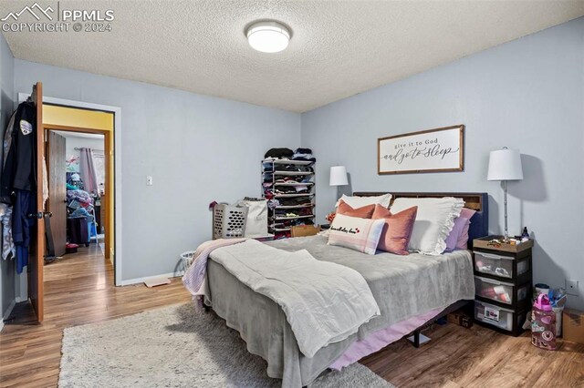 bedroom with a textured ceiling and wood-type flooring