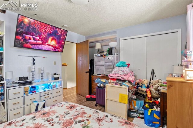 bedroom with a textured ceiling, light hardwood / wood-style flooring, and a closet